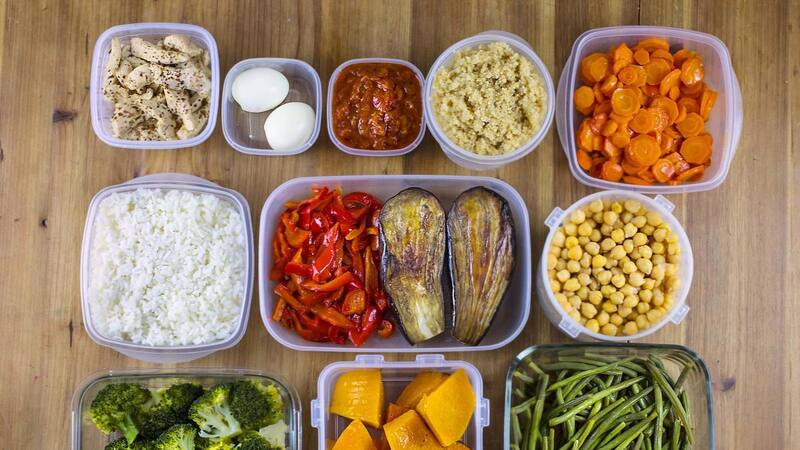 Comidas organizadas en recipientes sobre mesa de madera