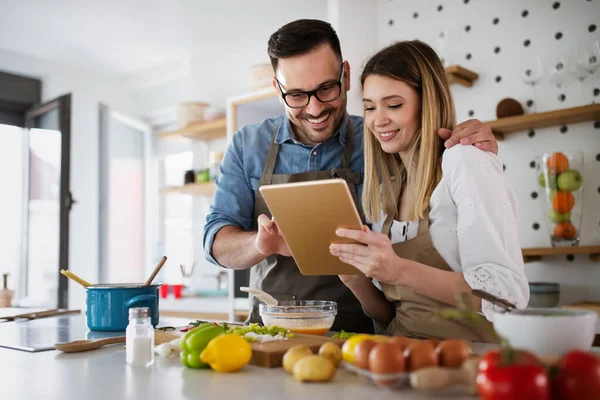 Pareja usando una tablet en la cocina para organizar comidas